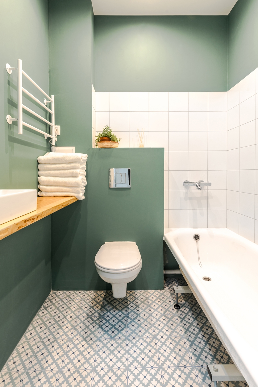 Minimalistic elegant design of bathroom in wormwood green color, installation, white bath. Wall paint for wet room using