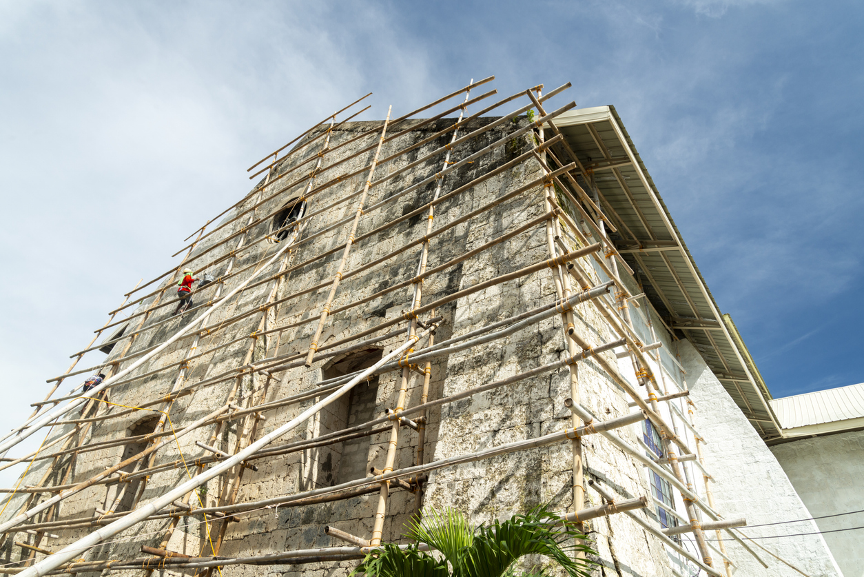 A Filipino workman on bamboo scaffolding,redecorates the end wall