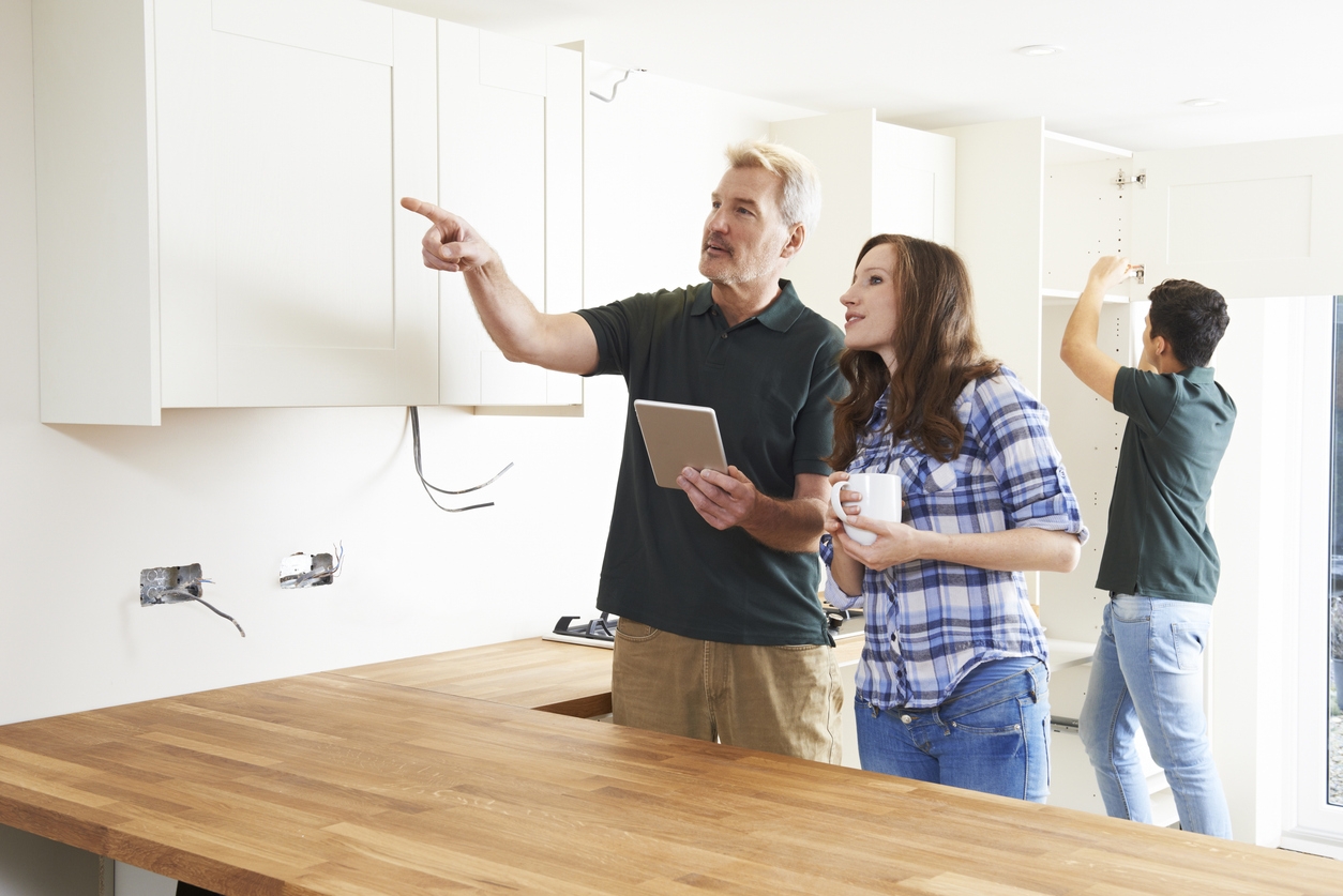 Woman With Carpenter Looking At Plans For Kitchen