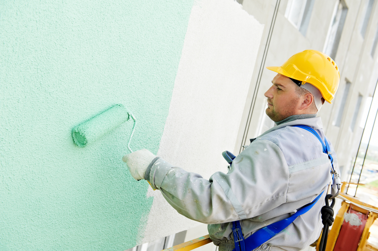 Worker painting building facade with green tone in the Bay area